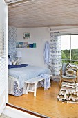 Blick von Terrasse in maritim gestalteten Schlafraum mit Bett in Blautönen