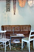 Simple kitchen chairs and leather couch around delicate retro tea trolley