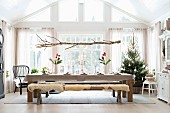 Branch suspended above festively set dining table an Christmas tree in background