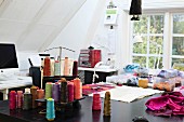 Various reels of thread and fabric remnants on sewing table in office