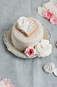 A cake decorated with fondant icing, a heart-shaped biscuit and sugar roses