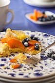 Sweet omelette with blueberries, peaches and icing sugar, partially eaten