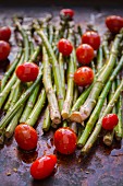 Asparagus and organic grape tomatoes with olive oil and spices on a baking tray