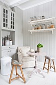 Gemütliche Küchenecke im skandinavischen Landhausstil mit Polstersessel, Tisch und Holzhocker