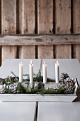 Four white candles in DIY candelabra made from half a birch log on wooden tray