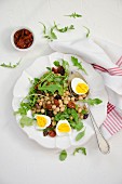 Chickpea salad with dried tomatoes, rocket, olives and hard-boiled egg