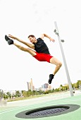 A man trampolining in a park against a skyline