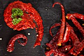 Chilli paste and chilli peppers on a black surface