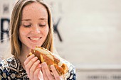 A young woman with a white sausage hot dog