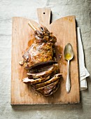 Sliced leg of lamb on a chopping board with a spoon