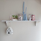 Romantic, country-house Easter arrangement of spring flowers and house-shaped lantern on small bracket shelf