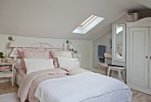 Romantic double bed with pink bed linen in shabby-chic attic room