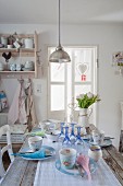 Pendant lamp above set dining table in vintage-style shabby-chic kitchen-dining room