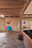 Türkisfarbener Sessel in renoviertem Wohnraum mit Holzverkleidung