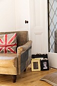 Union flag cushion on old leather armchair next to picture frame leaning against door frame