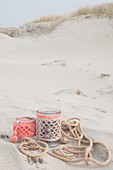 Windlichter mit Häkelhüllen in Pastelltönen am Strand