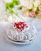 A meringue cake with whipped cream, pink sugared almond and lychees