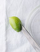 A green olive being halved with a knife (close-up)