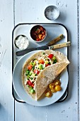 Burrito with fish, leek, pepper, peas and tomato served with tomato salsa and sour cream