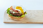 A hamburger with lettuce, ham, cheese and a fried egg