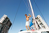 Junger Mann mit Bermudahose auf einer Yacht