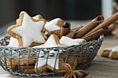 Cinnamon stars and cinnamon sticks in a basket on a rustic wooden table