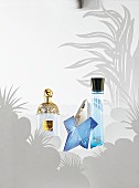 Summer scents – three bottles of perfume on a grey botanic-patterned surface