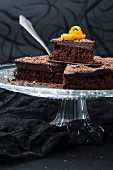 A sliced chocolate orange cake with ganache on a cake stand