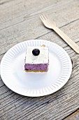 A slice of blueberry cheesecake on a paper plate