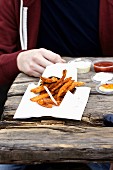 Sweet potato chips with dips on a wooden table