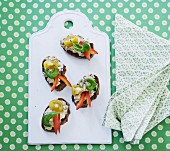 Slices of bread topped with spread, vegetables and basil