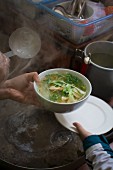 Dampfende Schüssel Pho (Suppe, Vietnam) in einer Strassenküche