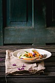 Gehobelte Gemüsebandnudeln von Möhre, Rettich und Zucchini auf Teller mit Fliederblüten