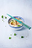 Vegetable noodles with parsley and sesame seeds in an oriental bowl with chopsticks