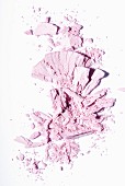 Rose-coloured eye shadow crumbled on a white surface