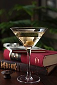 A dry Martini with olives and classic books in a den