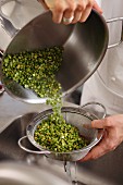 Cooked green lentils being drained