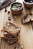 Wholemeal crackers with almonds, pumpkin seeds and dried cranberries on a wood surface