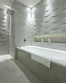 Bathtub in designer bathroom with marble tiles and 3D structured tiles