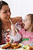 Frau und kleines Mädchen essen mit Essstäbchen