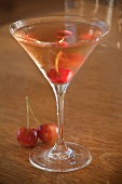 A cocktail made with vodka and cherries in a Martini glass
