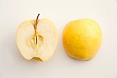 A halved Golden Delicious on a white surface