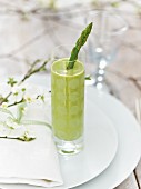 A glass of pea and coconut soup with green asparagus