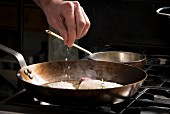Scallops being seasoned in a pan