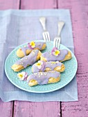 Eclairs with violet icing and dried pansy petals