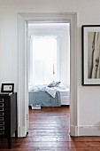 View through open interior door into bedroom with wooden floor