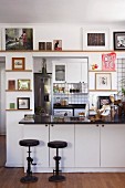 Vintage bar stools with cast iron bases in front of counter with white base units; doorway leading to kitchen in background