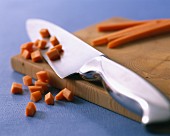 A knife and diced carrots on a chopping board