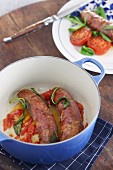 Sausages wrapped in ham with tomatoes and sage