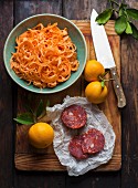 Grated carrots, sausage and oranges on chopping board